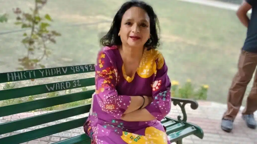 An elderly woman sitting at a park table, reflecting on the reasons to choose an Indian-based elderly care home