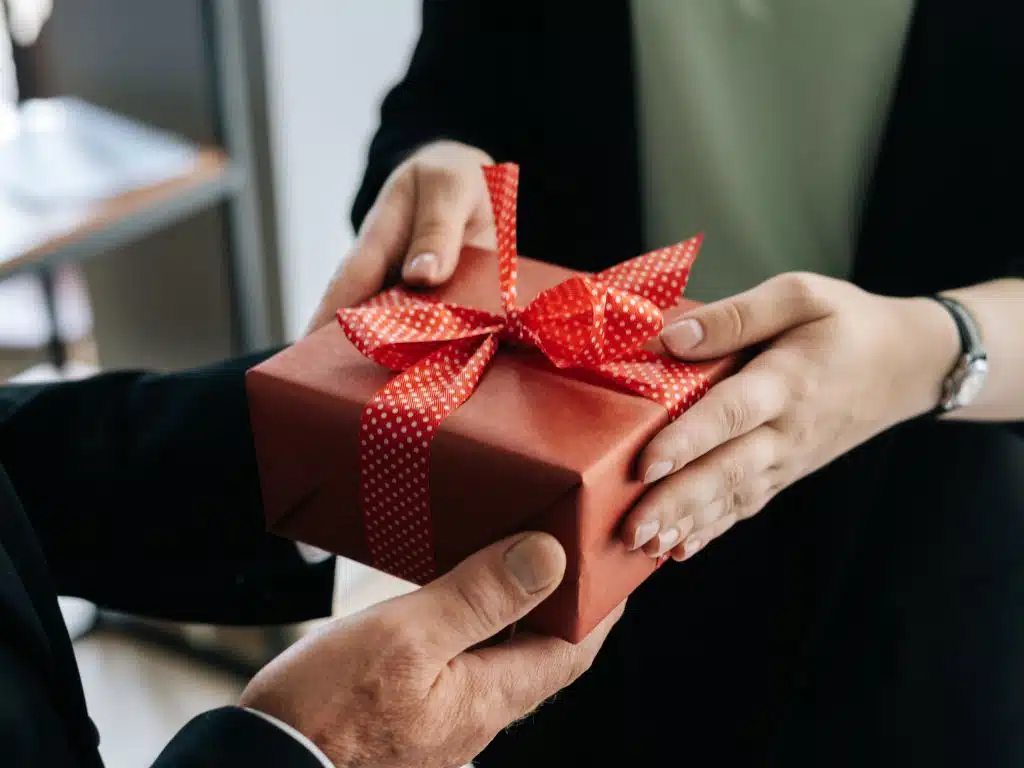 Presents that senior citizens appreciate: close-up of red gift box being handed to an older adult.