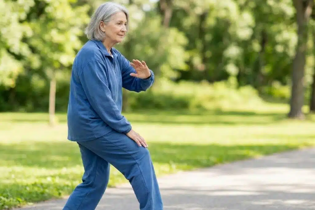 Older woman performing the “brush knee and push” movement with a slow forward step and relaxed arm position