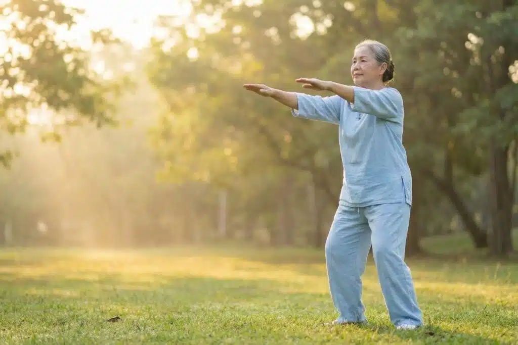 Older adult calmly practicing the Tai Chi opening posture outdoors