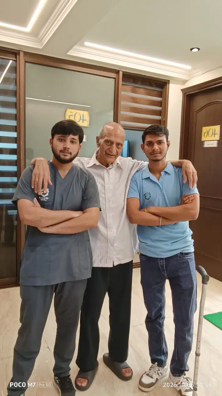 Senior resident standing with the support of two caretakers at Gracias Living in Gurgaon